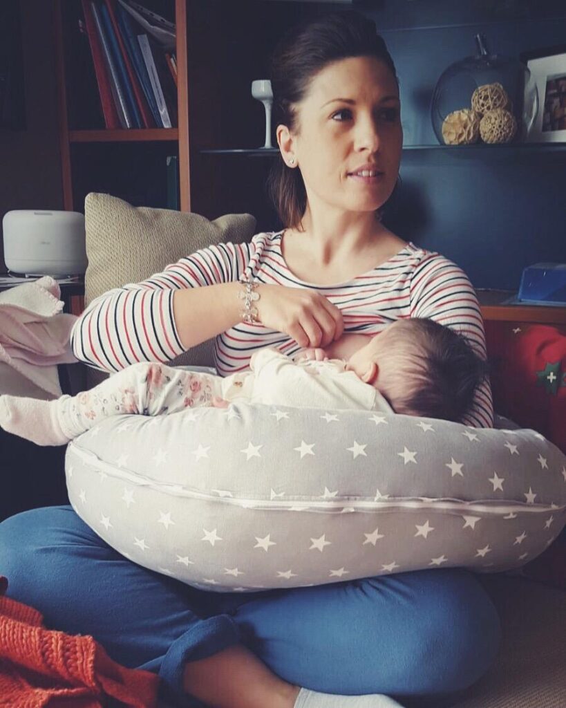 mamma che allatta la sua bambina seduta sul divano